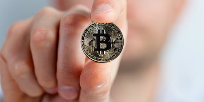 en-man-håller-i-en-bitcoin